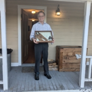 man holding case with some artifacts on a porch