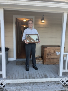 man holding case with some artifacts on a porch