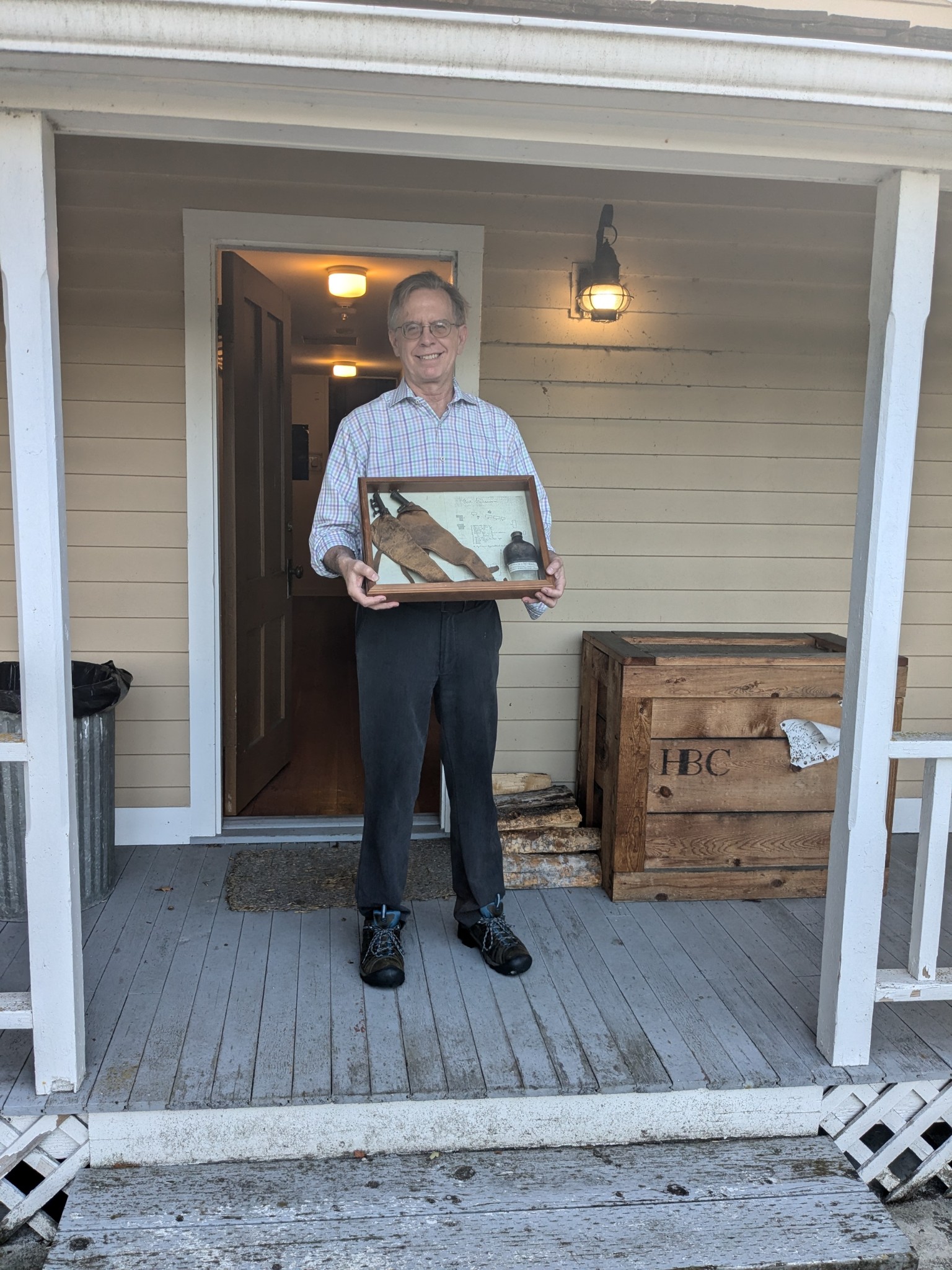 man holding case with some artifacts on a porch